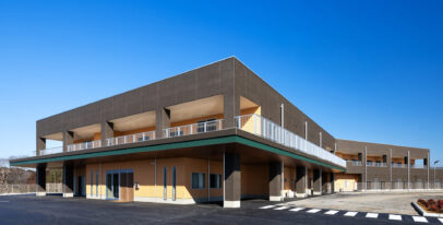 モダンデザインの介護施設外観。木調とコンクリートを組み合わせた2階建て建物。